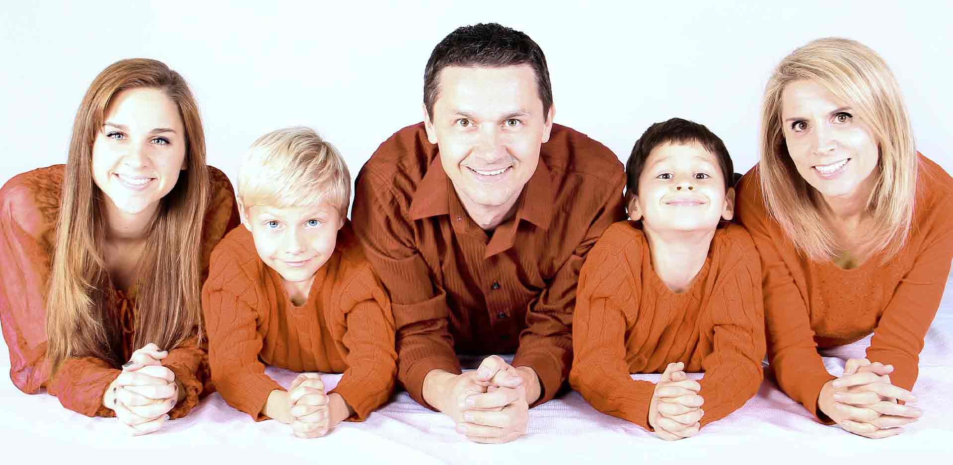 smiling family in orange sweaters lying on their stomachs
