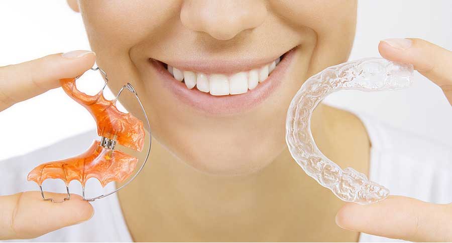 smiling girl holding two types of retainers